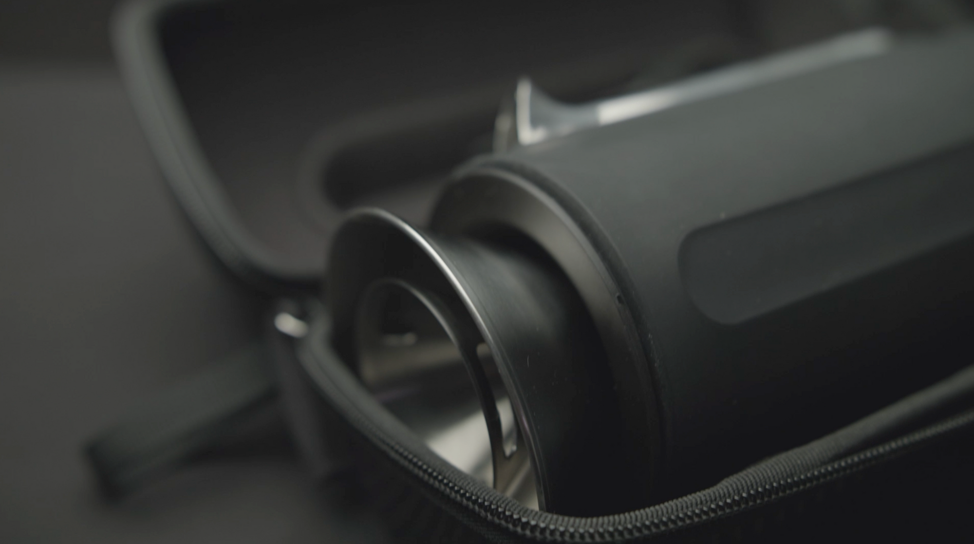 Close-up of a black cylindrical component of the Pakt Coffee Kit inside a partially unzipped black carrying case.