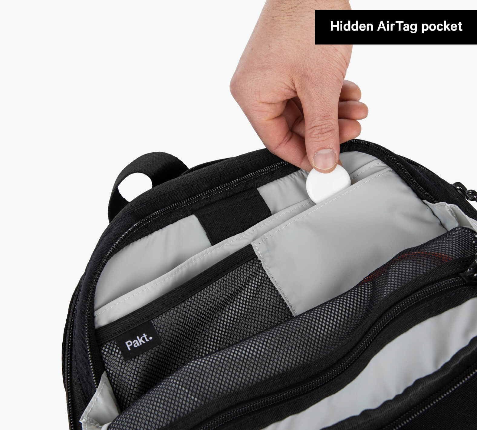 Hand placing a round AirTag into hidden pocket inside Everyday 22L Backpack; Pakt. label visible; Hidden AirTag pocket.
