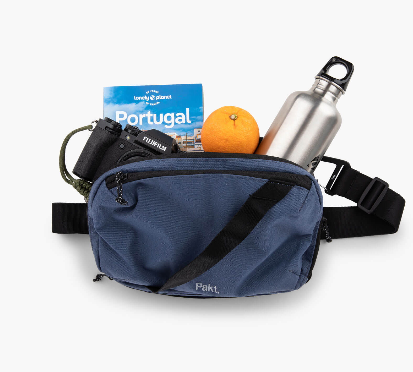 Blue Everyday 5L Sling bag with a camera, Portugal guidebook, orange, and metal water bottle inside