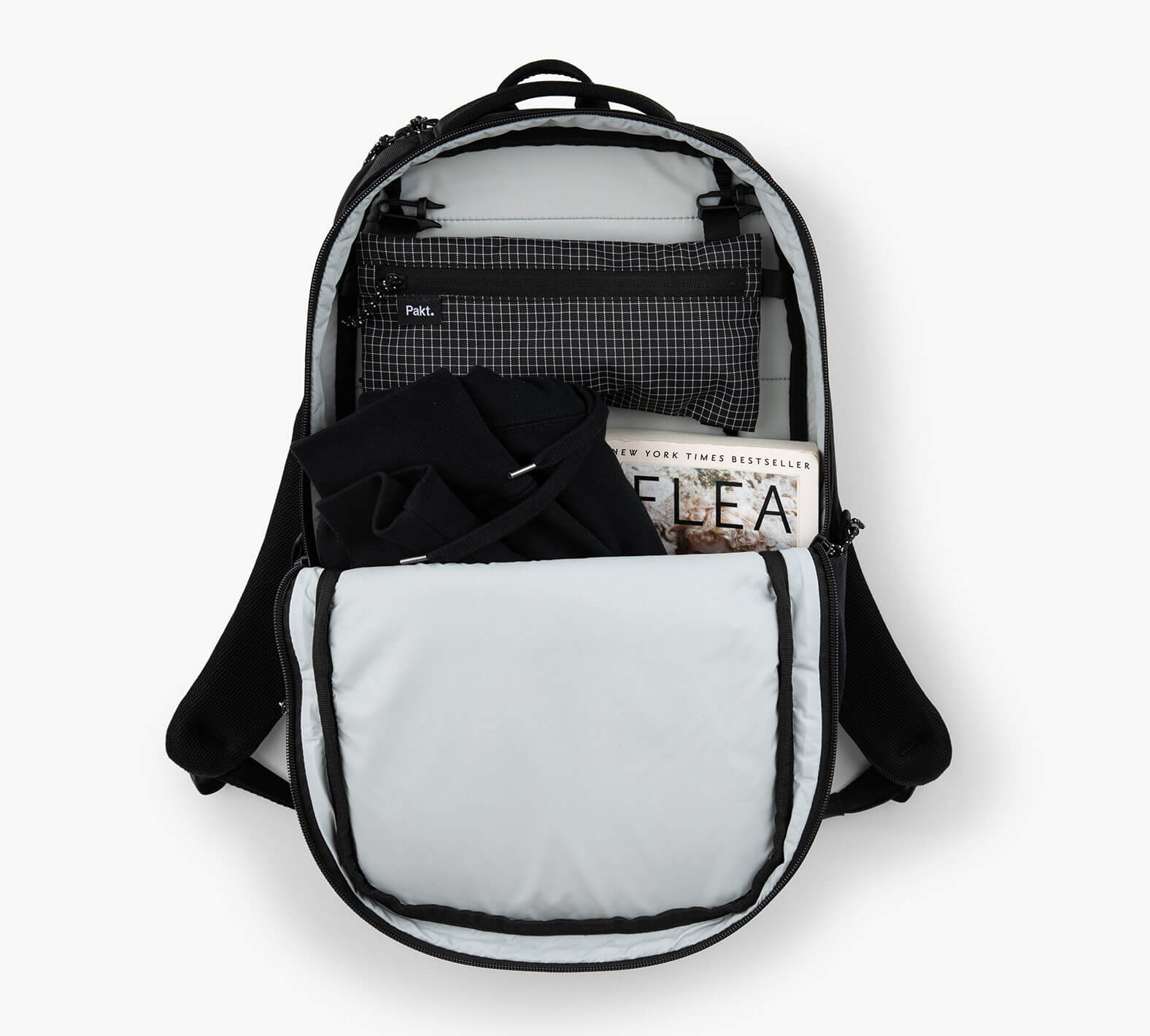 Open Everyday 22L backpack showing front pocket with folded black shirt and packet labeled FLEA