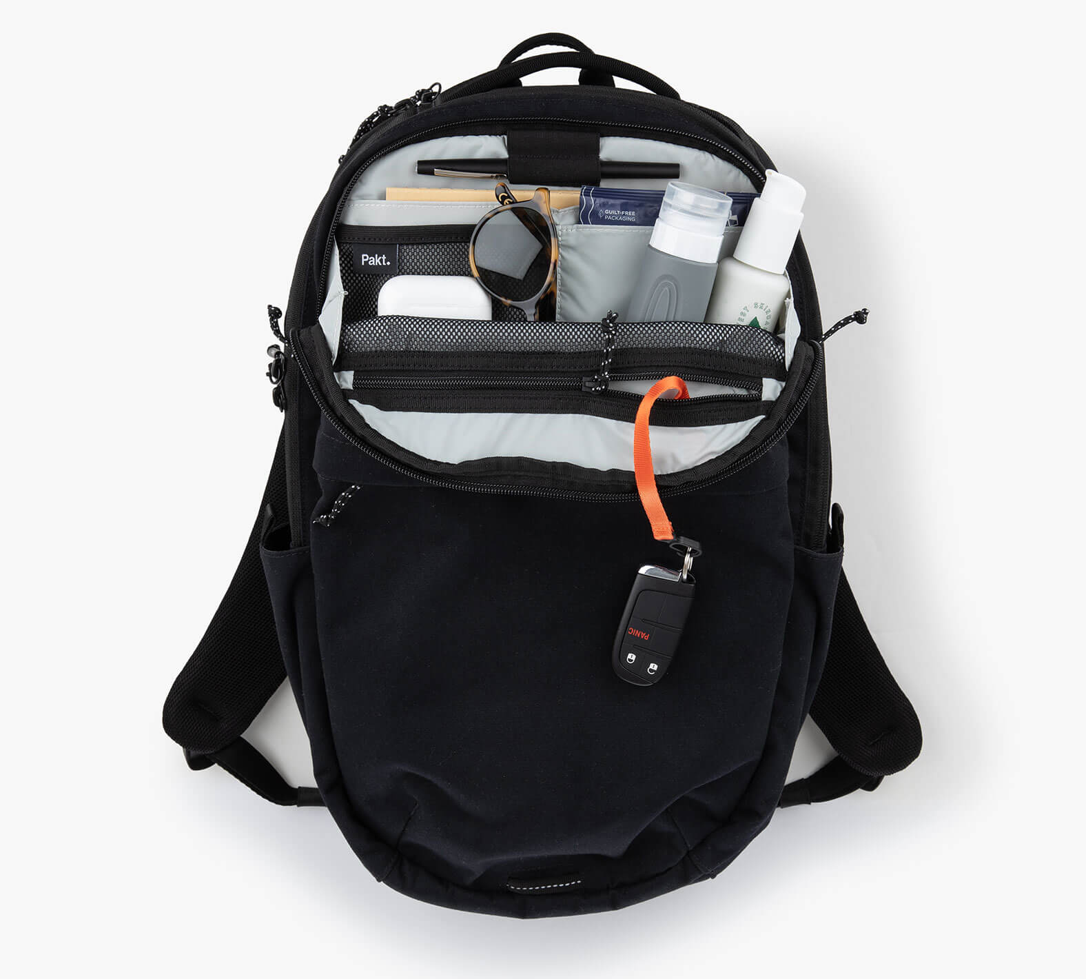 Open Everyday 22L backpack showing organized interior with notebook, watch, water bottle, toiletry tube, and orange key leash