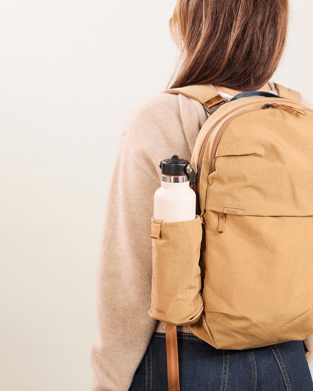 Rear view of MODE Convertible Bag 14L in mojave showing side bottle sleeve with water bottle