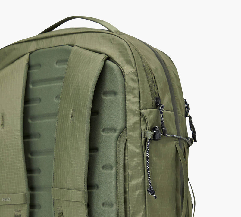 Olive-green backpack back panel with molded foam padding, padded shoulder straps, and a side zipper pocket.