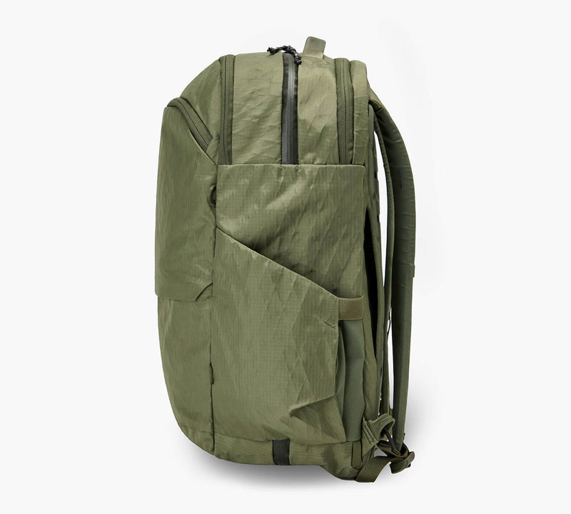 Olive-green backpack in profile with exterior pocket and padded shoulder straps.