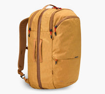 Mustard-yellow backpack with two main zip compartments, padded shoulder straps, and several zippered pockets.