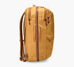 Tan vertical travel backpack with brown trim, padded shoulder straps, front zipper pocket, and side handle.