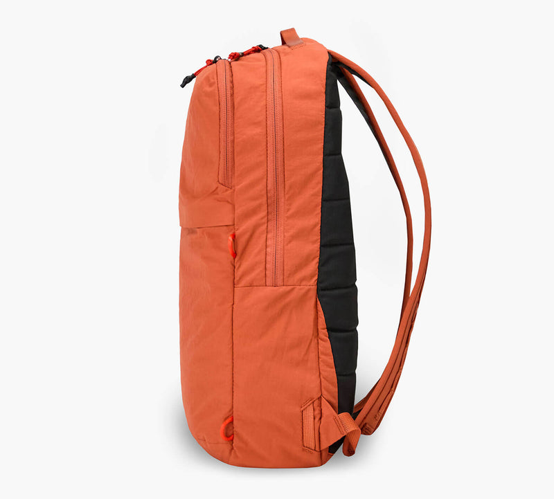 Orange backpack, side view, padded black back panel and two shoulder straps.