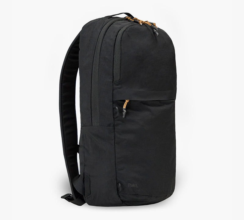 Black commuter backpack with padded shoulder straps, front zip pocket and tan zipper pulls.