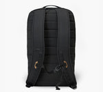 Black padded backpack, rear view showing shoulder straps, sternum strap, and luggage pass-through