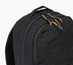 Close-up of black backpack top showing two zip compartments and tan paracord zipper pulls