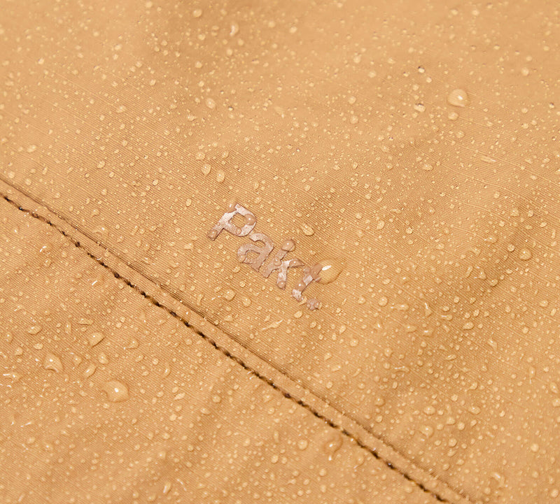 Close-up of the Mojave aeroweave fabric with water droplets and the word 'Pakt' embroidered.