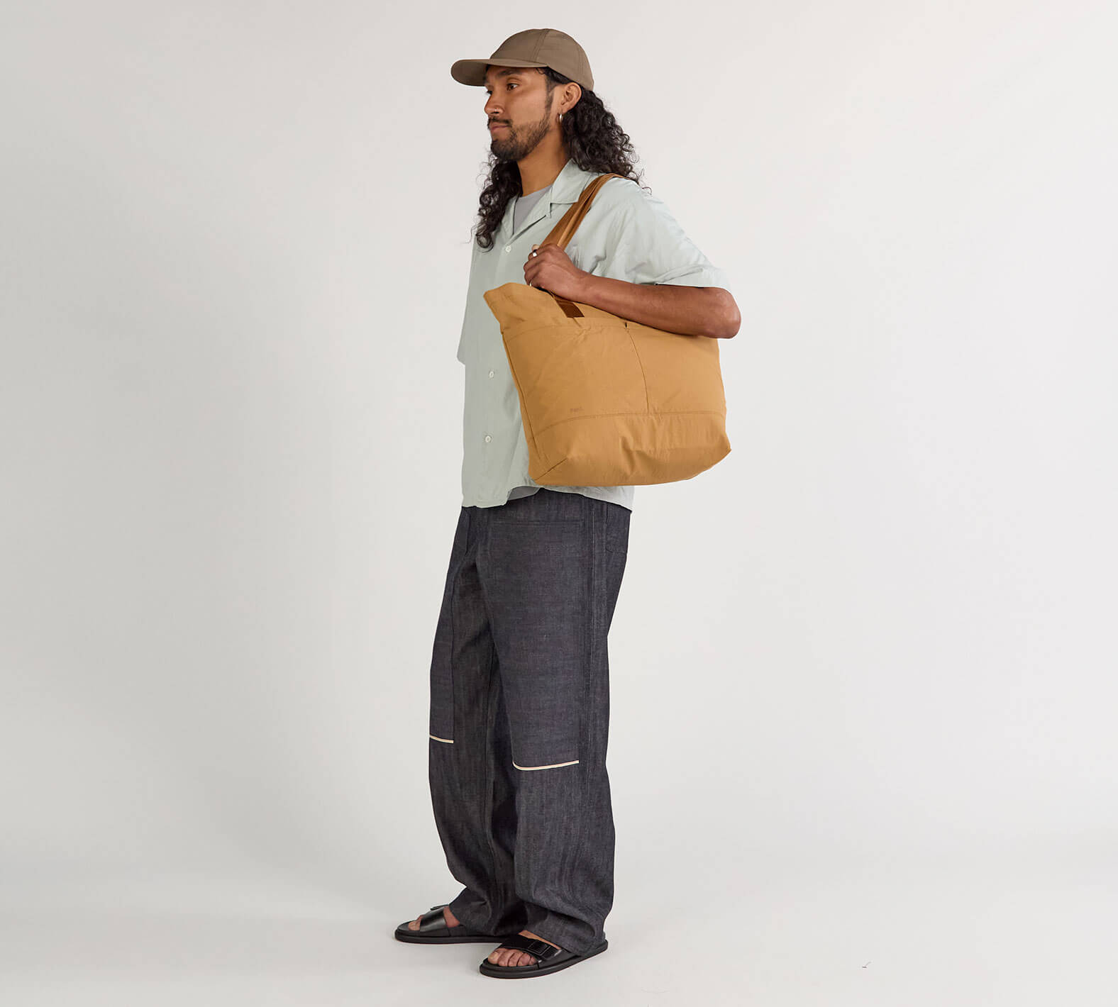 Model carrying Stash Packable Tote 20L in Mojave over shoulder, showing size and zippered top