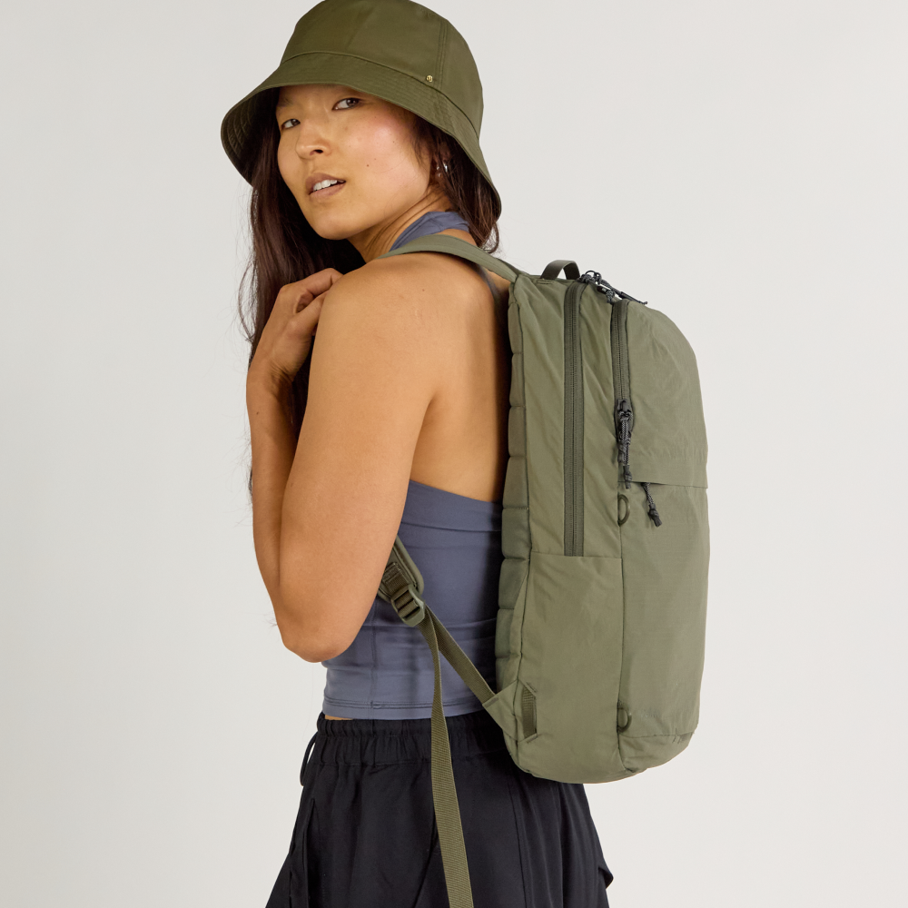 Side view of Stash Packable Backpack 16L in cypress on model with padded straps and slim profile against gray background