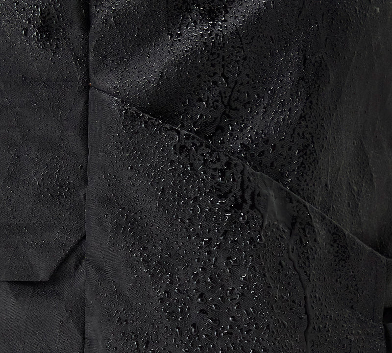 Close-up of black Aero Travel Backpack material with water droplets showing water resistance.
