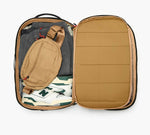 Pakt One Travel Backpack+ open, mojave interior packed with tan sling, gray pants, and white sneakers with green N logo