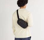 Black Stash Sling crossbody bag worn across the back over a cream long-sleeve shirt