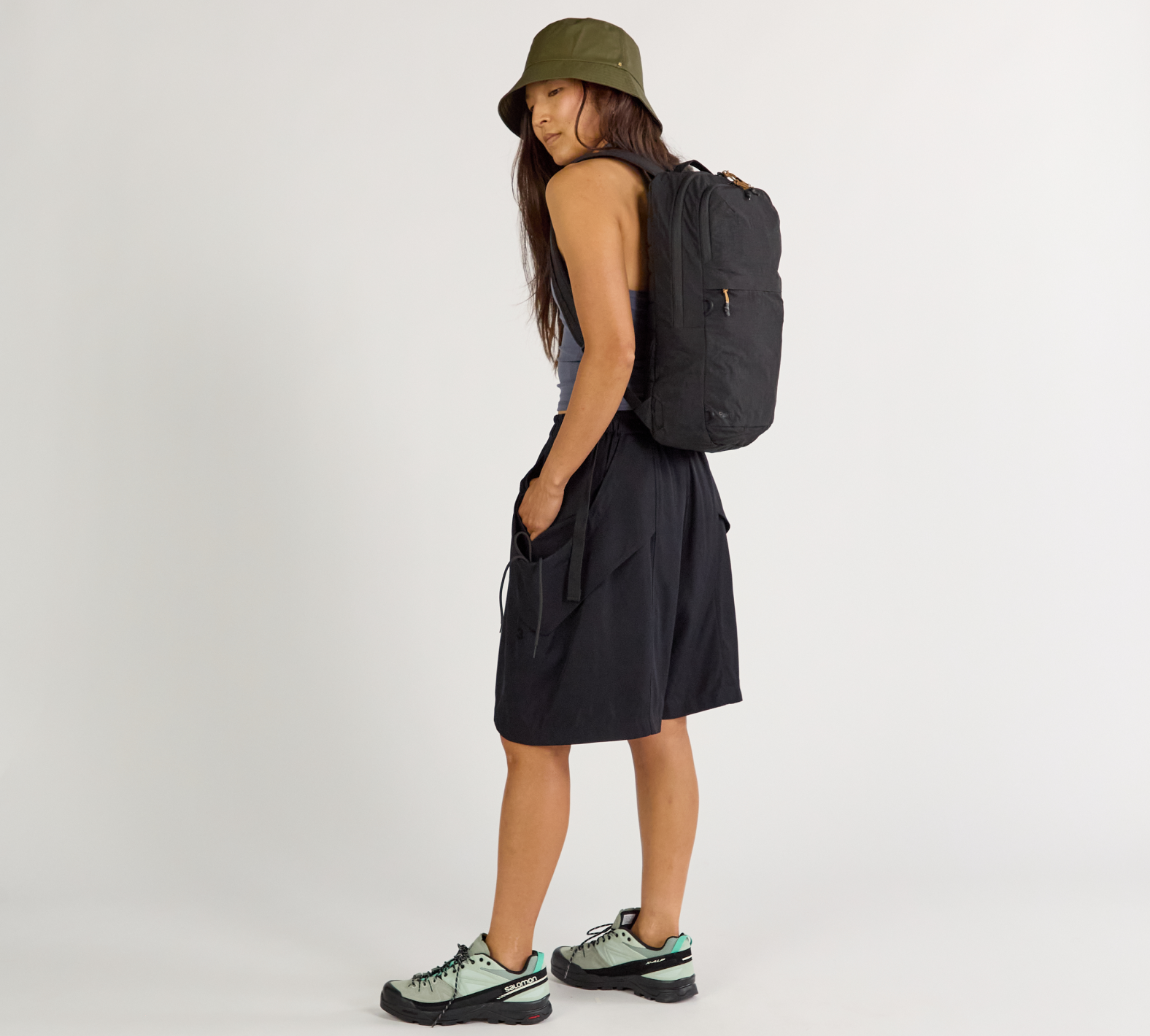 Side view of Stash Packable Backpack 16L in Black showcasing slim packable profile and front zip pocket on white background