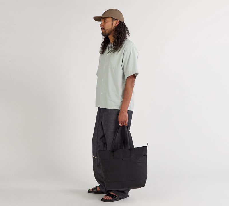 A model standing holding the Stash Tote in black.