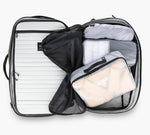 Open carry-on suitcase with gray packing cubes and mesh divider, showing Pakt. brand tag