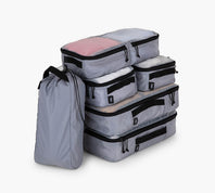 Three-quarter view of a 6-piece packing cube set showing stackable zippered cubes in multiple sizes with a slim carry pouch on a white background