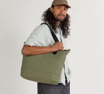 A model wearing the Stash tote in cypress against a plain background.