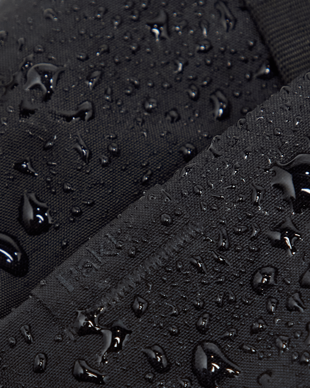 Close-up of MODE Shoulder Bag 12L fabric showing water beading on PFAS-free water-resistant rNylon