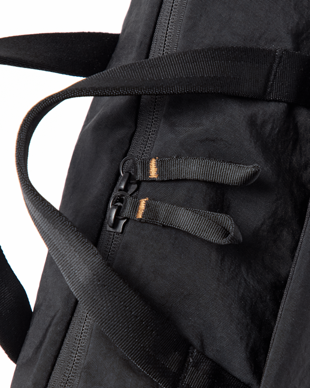Close-up of MODE Shoulder Bag 12L showing dual zipper pulls with fabric tabs and padded shoulder strap on white background