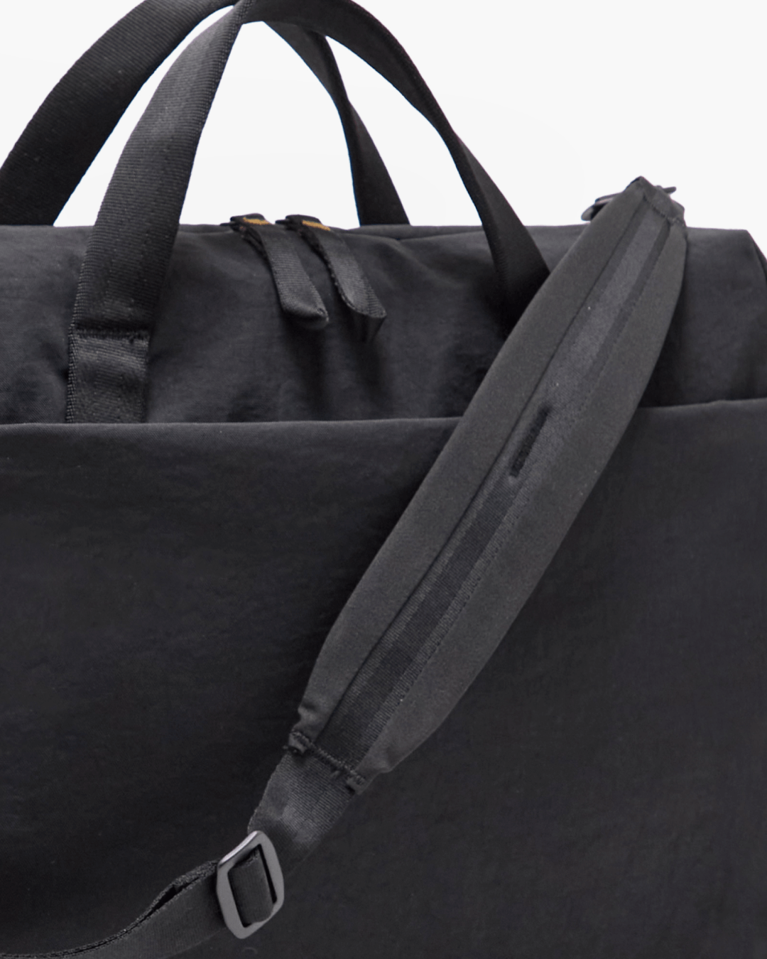 Close-up of MODE Shoulder Bag 12L showcasing padded shoulder strap, top handles, and exterior pocket on a white background