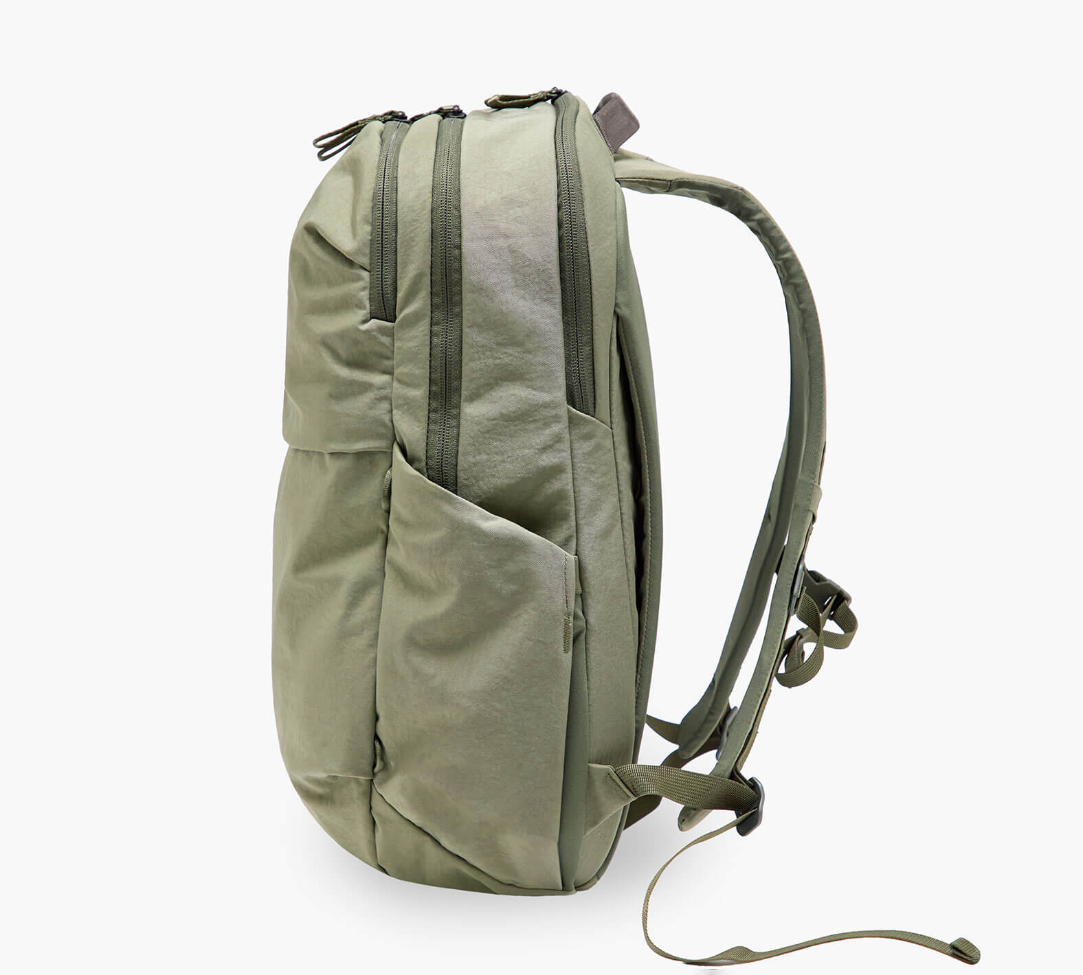 Olive-green backpack shown from side with dual zip compartments, external side pocket, and padded shoulder straps.