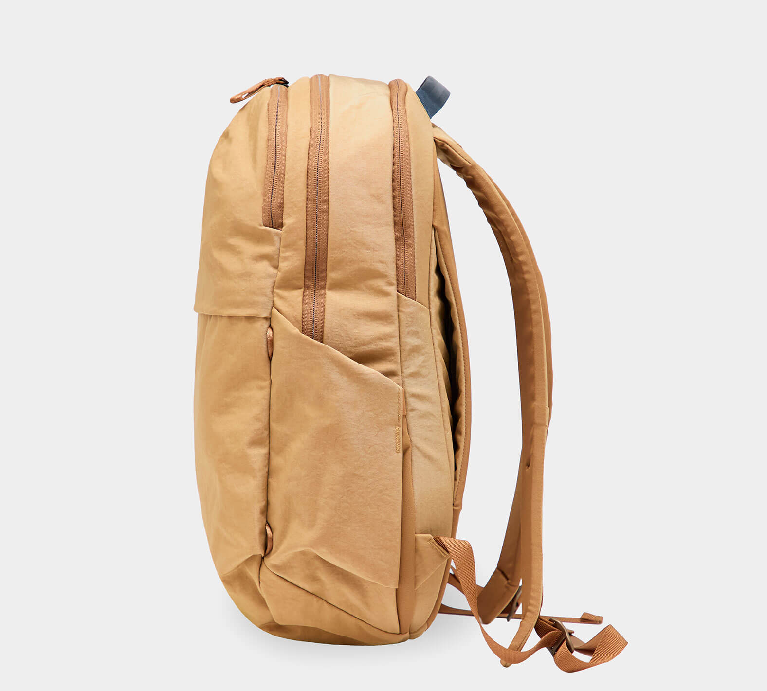 Side view of MODE Backpack 22L in Mojave showcasing two zippered compartments, external water bottle pocket and padded shoulder straps