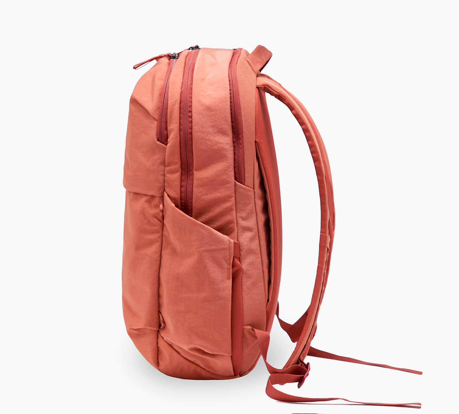 Coral backpack, side view; two zippered compartments, exterior water-bottle pocket, and padded shoulder straps.