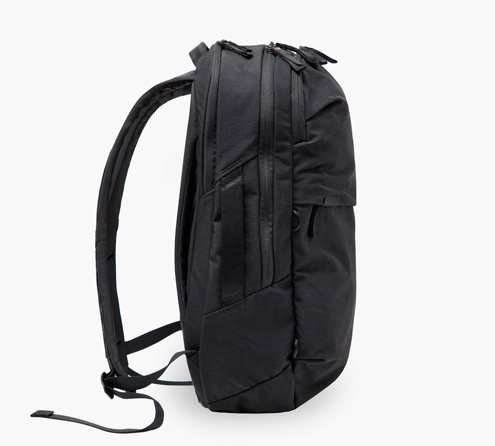 Black backpack, side profile with padded shoulder straps and multiple zippered compartments.