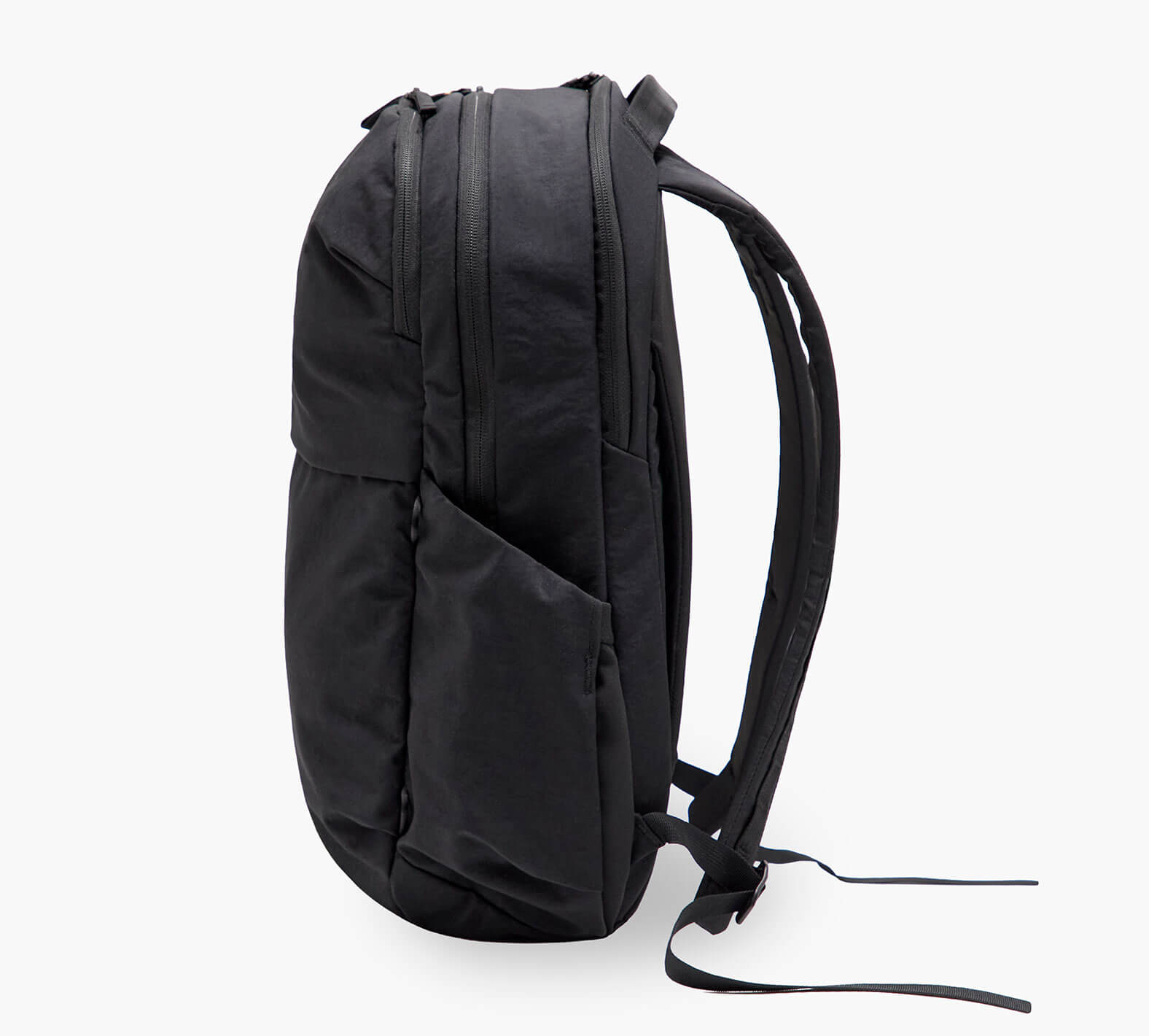 Black backpack side view showing padded shoulder straps, front pocket, and side water-bottle pocket.