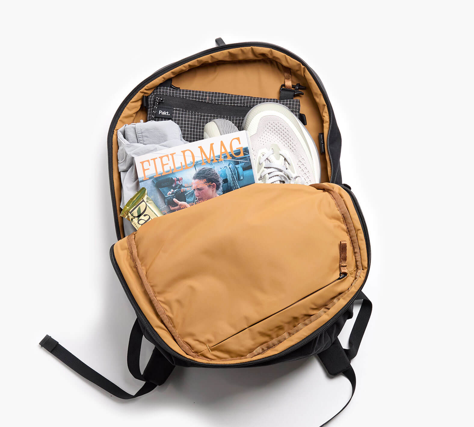 Top-down of MODE Backpack 22L open, sumac interior showing padded laptop sleeve and packed with shoes, sweater, and FIELD MAG