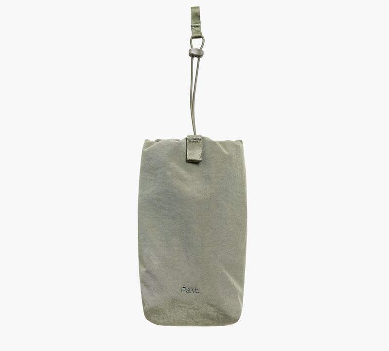Light gray fabric hanging travel pouch with top strap and metal clip and small logo near bottom.
