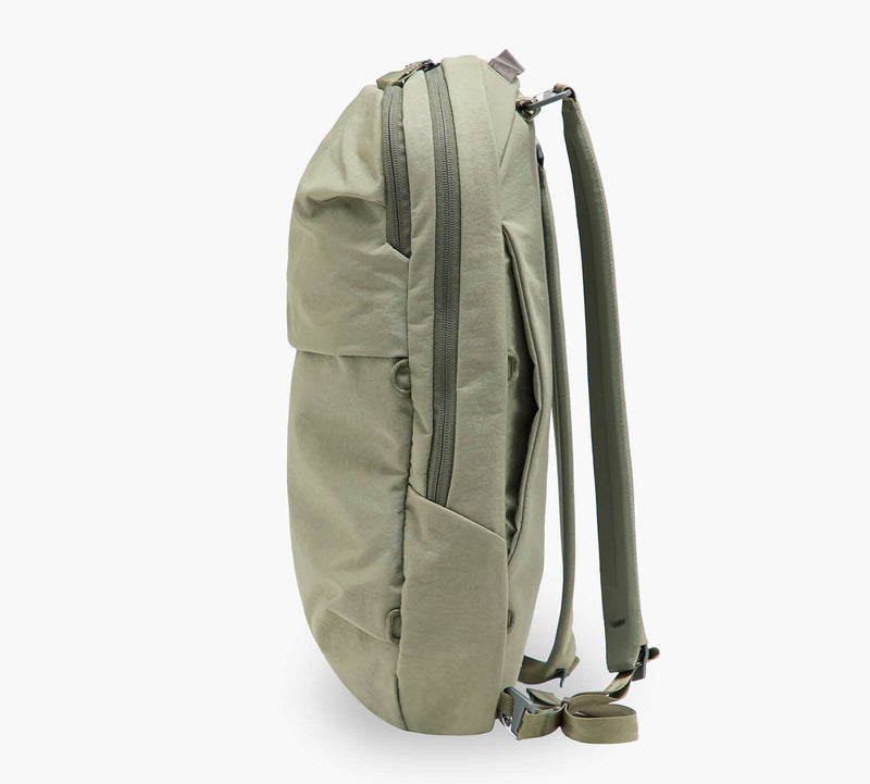 Olive-green backpack, side view showing zippered side pocket, water bottle sleeve, and padded shoulder straps.