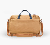 Tan canvas weekender duffel with navy top handles, adjustable tan shoulder strap, and front slip pocket.