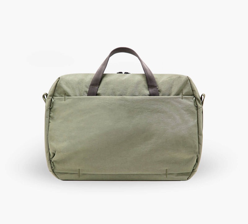 Olive-green canvas duffel bag with front exterior pocket and short brown handles, shown from the front.