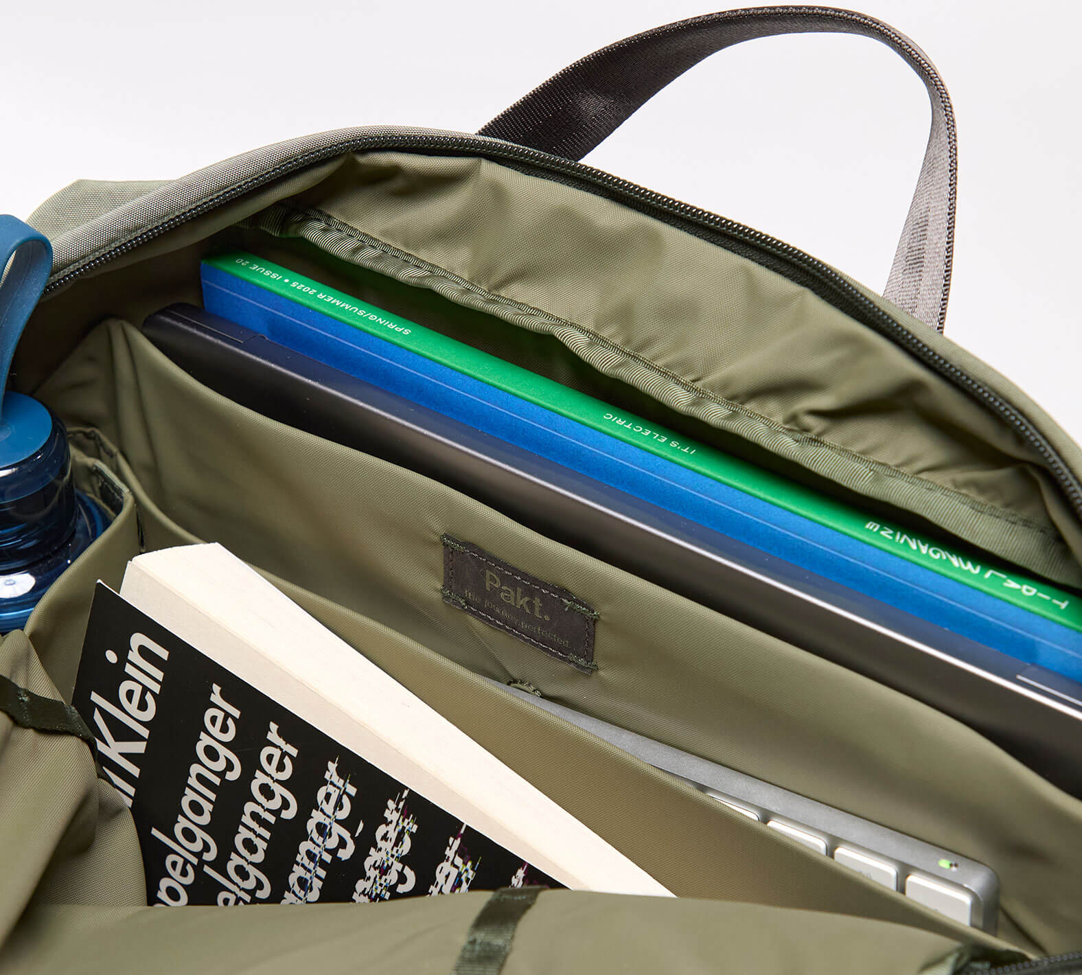 Top-down view of MODE Shoulder Bag 12L in cypress showcasing padded laptop sleeve, interior organizer pockets, and water bottle sleeve