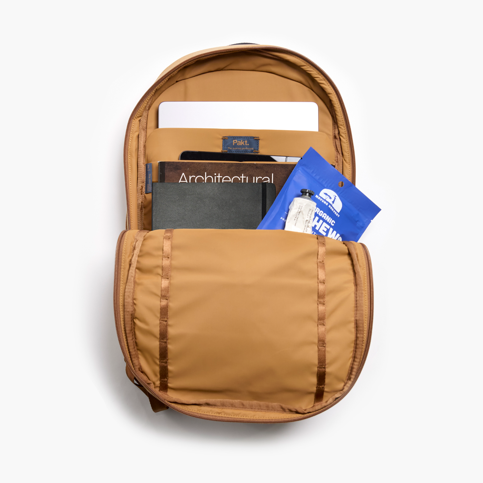 Top-down of MODE Convertible Bag 14L in mojave, open to show padded laptop sleeve with laptop, notebook, and snack on white background