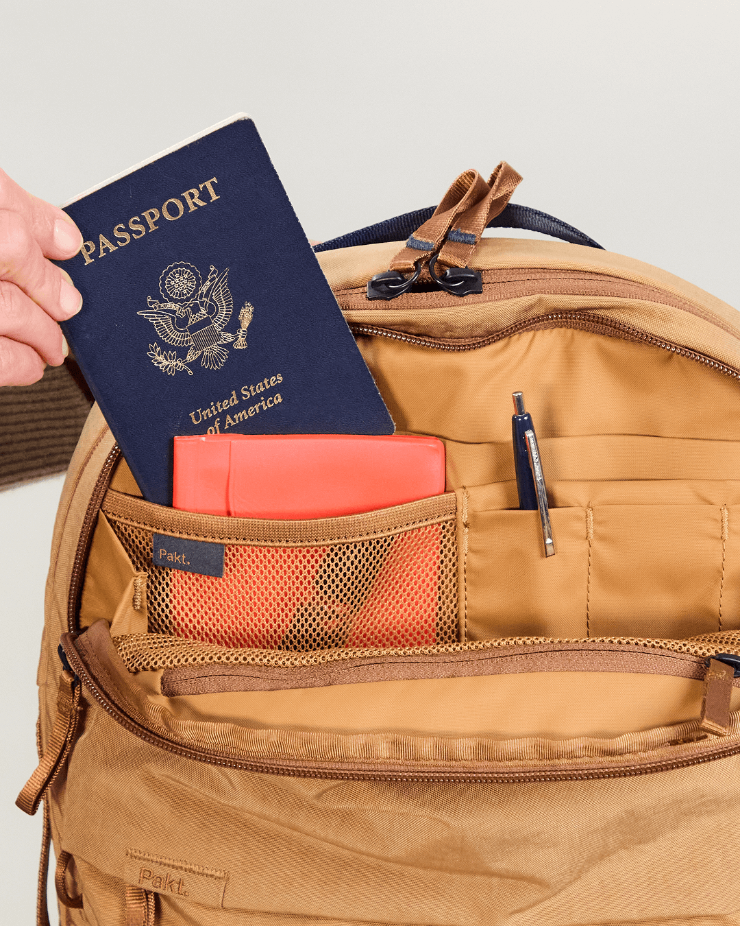 Close-up of MODE Convertible Bag 14L interior in Mojave showing organizer admin pocket with mesh sleeve holding a passport, small notebook, and pen