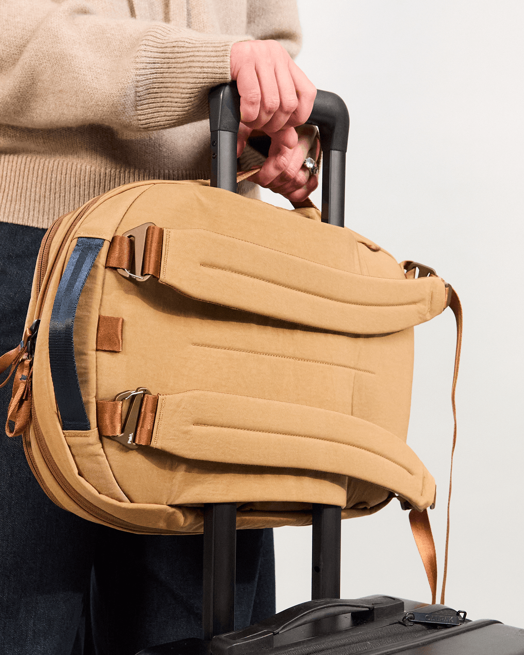Rear view of MODE Convertible Bag 14L in Mojave with folded backpack straps and luggage pass-through on suitcase handle