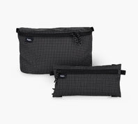 Front view of two clip-in pouches, one large 3D and one smaller flat, in black grid ripstop with top zippers and visible Pakt logo on white background