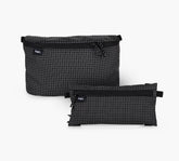 Front view of two clip-in pouches, one large 3D and one smaller flat, in black grid ripstop with top zippers and visible Pakt logo on white background