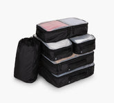 Set of five black zip packing cubes with clear tops and a black drawstring laundry bag for travel.