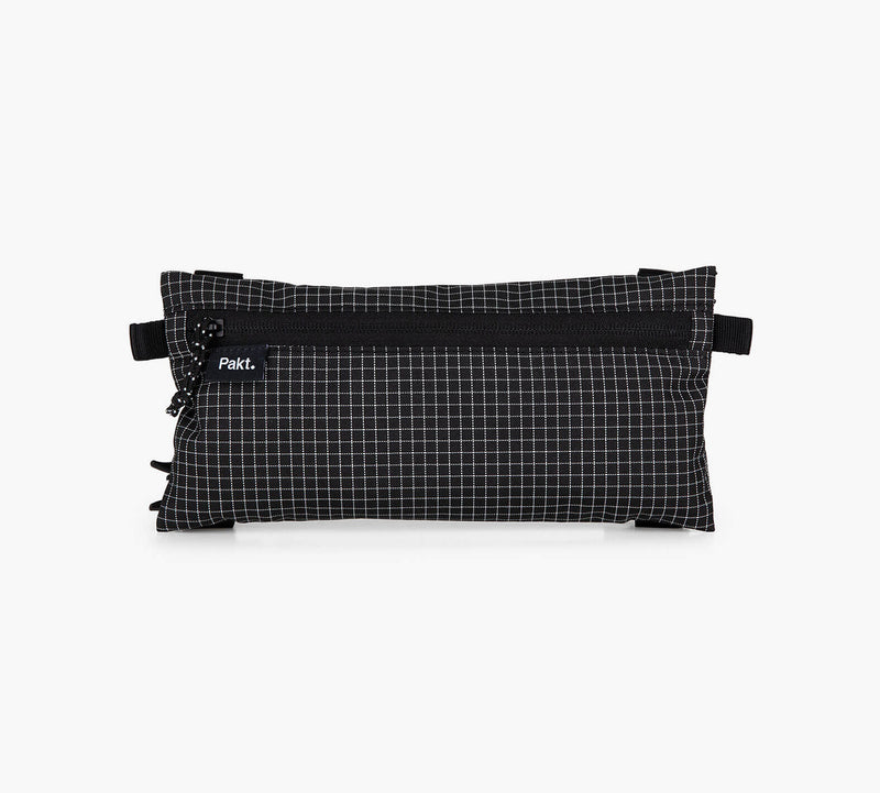 Flat clip-in pouch in black grid fabric with zipper and visible label reading 'Pakt.'