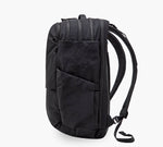 Black commuter backpack side view with angled exterior pocket and padded shoulder straps.