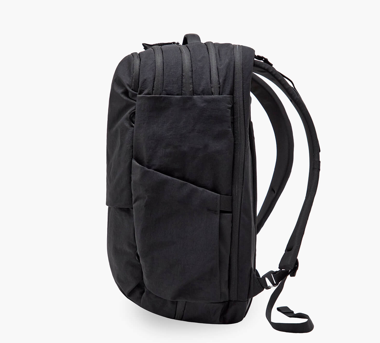 Black commuter backpack side view with angled exterior pocket and padded shoulder straps.