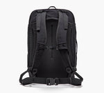 Black technical backpack viewed from the back with padded shoulder straps, sternum strap, and hip belt.