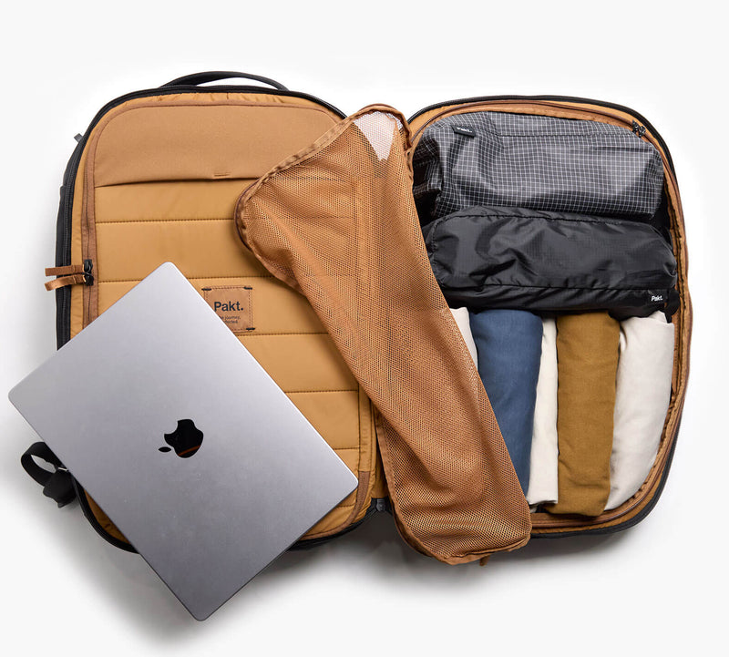 Open carry-on suitcase with a laptop being removed and neatly packed clothes inside